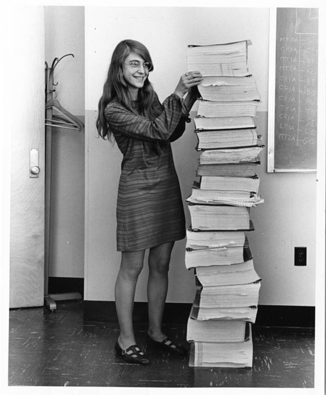 Margaret Hamilton à côté de l'ensemble du code source des missions Apollo